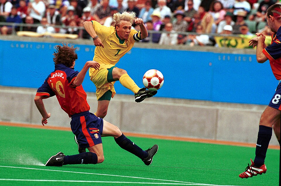 Vista aérea de un partido de fútbol con ambos equipos compactos